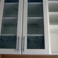 Cristaleira em armário branco com detalhes marfim, vidro transparente com desenho e prateleiras internas.